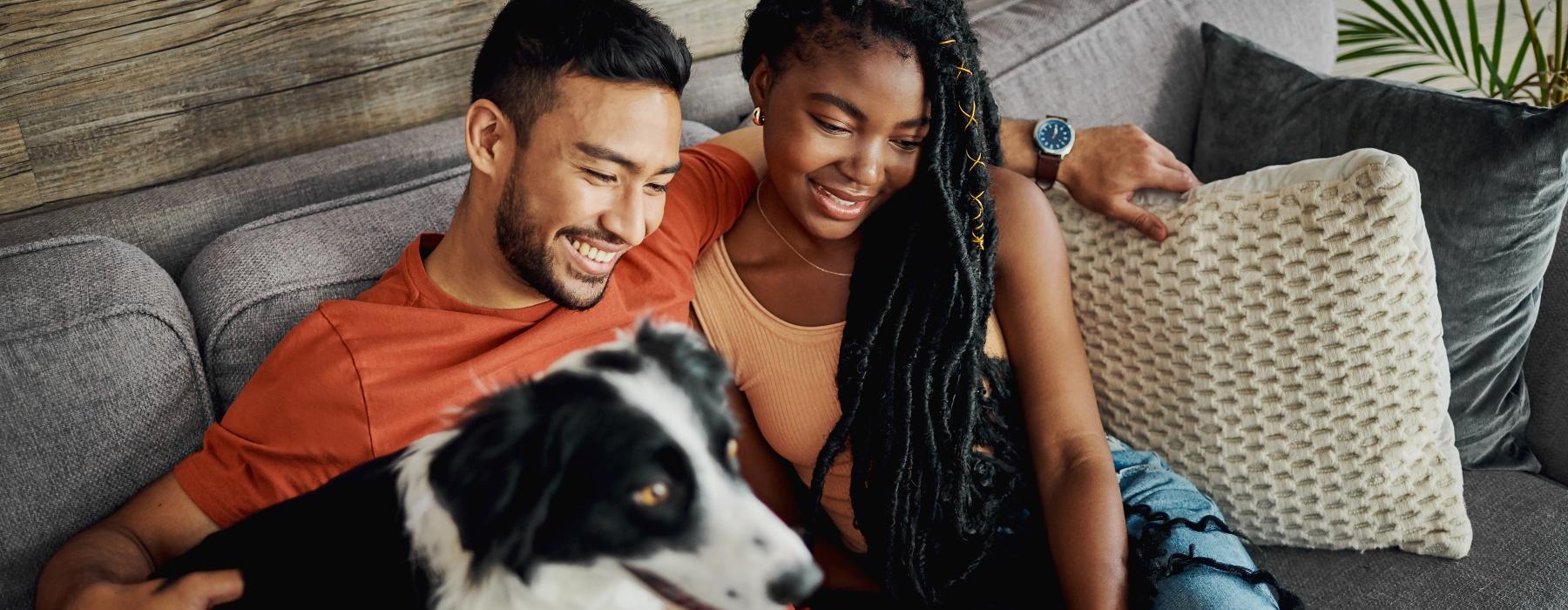 a man and woman sitting on a couch with a dog